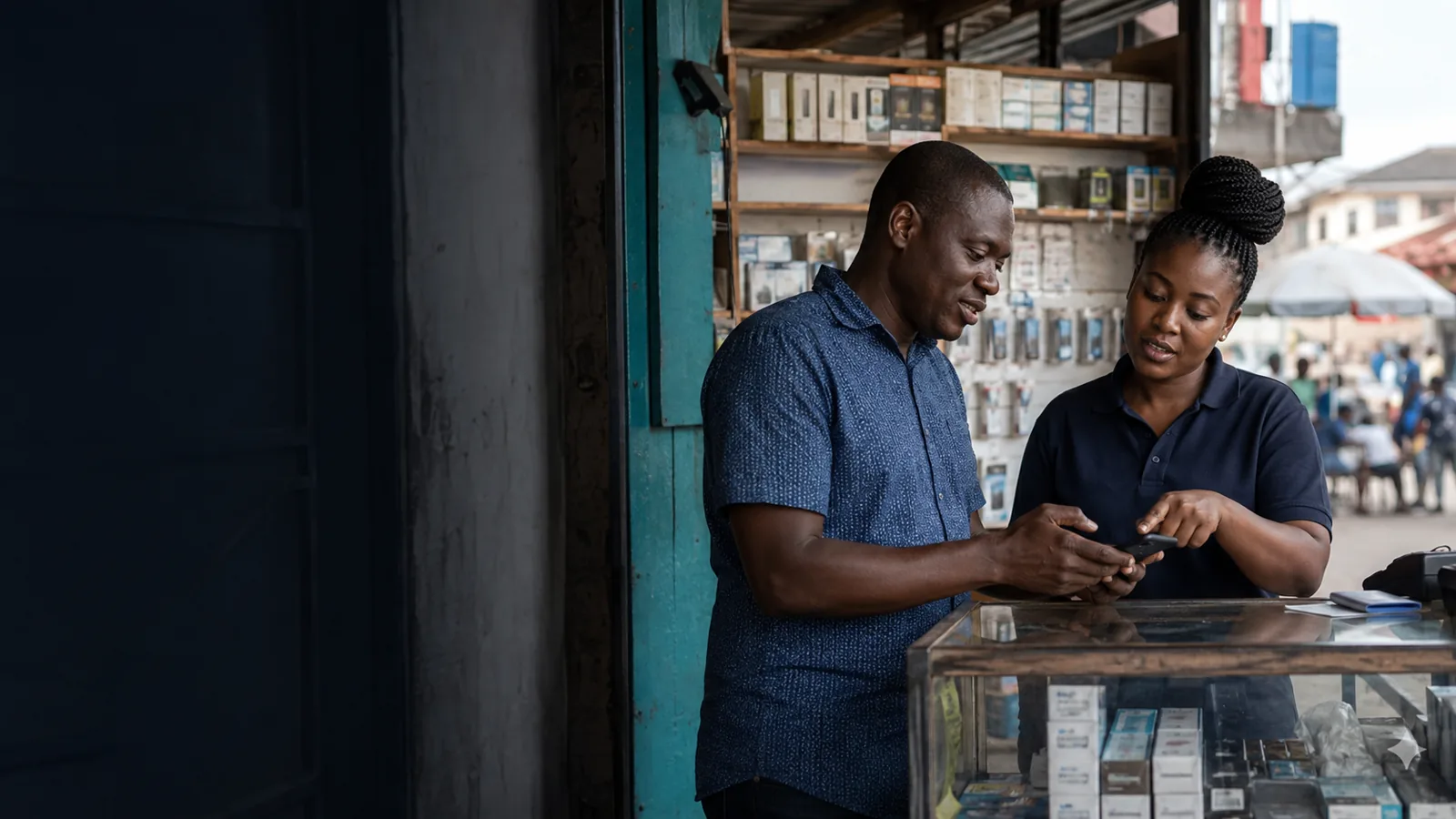 A shopkeeper serving a customer at a mobile-money counter.